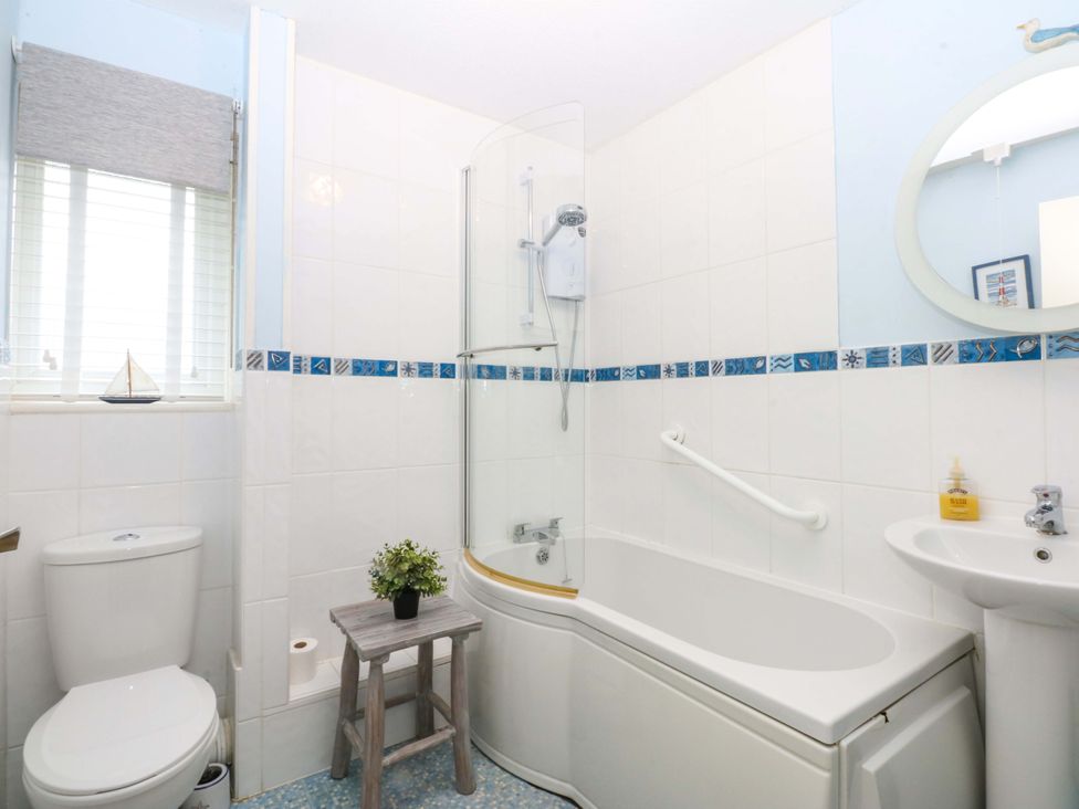 A bathroom with a bathtub, toilet, sink and shower at The Cottage On The Green in Borth-Y-Gest