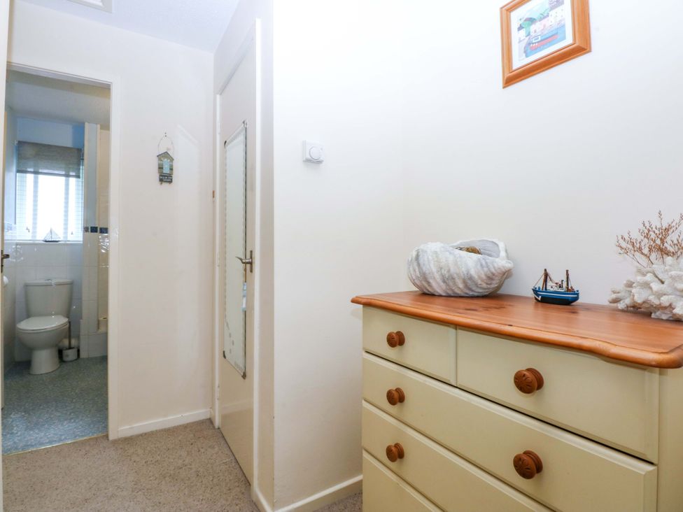 A hallway with a dresser and access to a bathroom at The Cottage On The Green Borth-Y-Gest