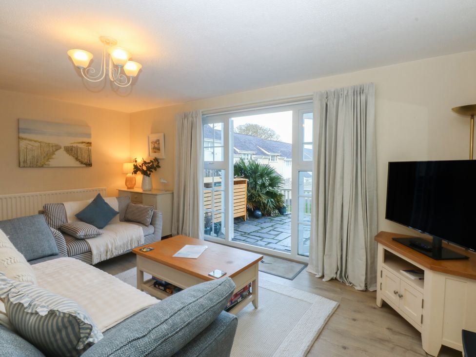 A living room with a sofa, television, and coffee table at The Cottage On The Green in Borth-Y-Gest