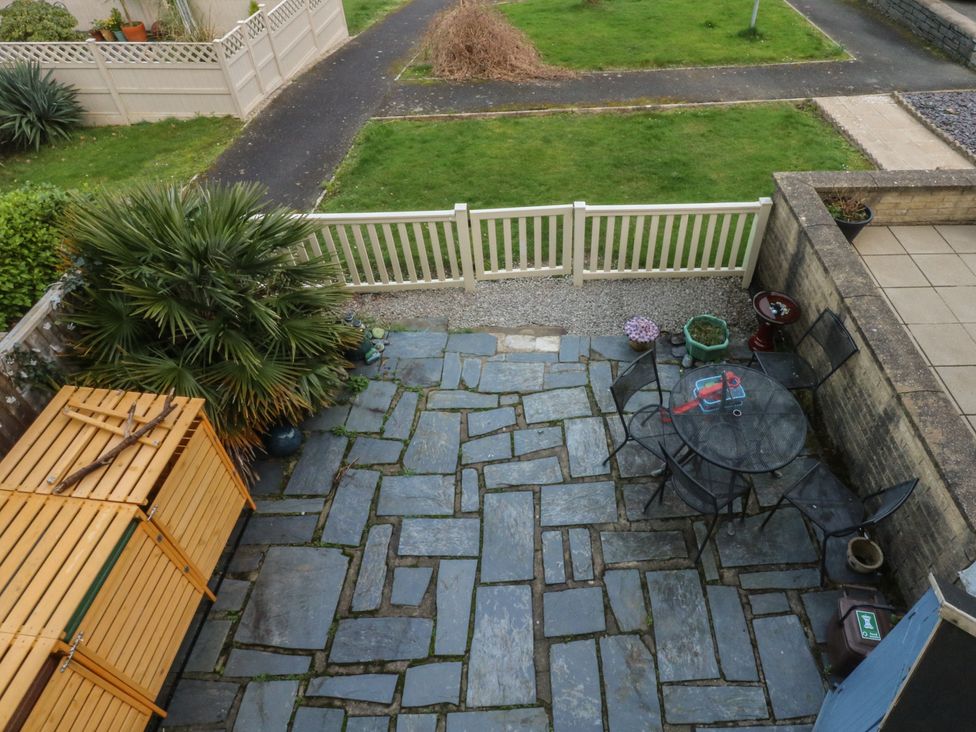 An outdoor patio with a glass table and metal chairs at The Cottage On The Green Borth-Y-Gest