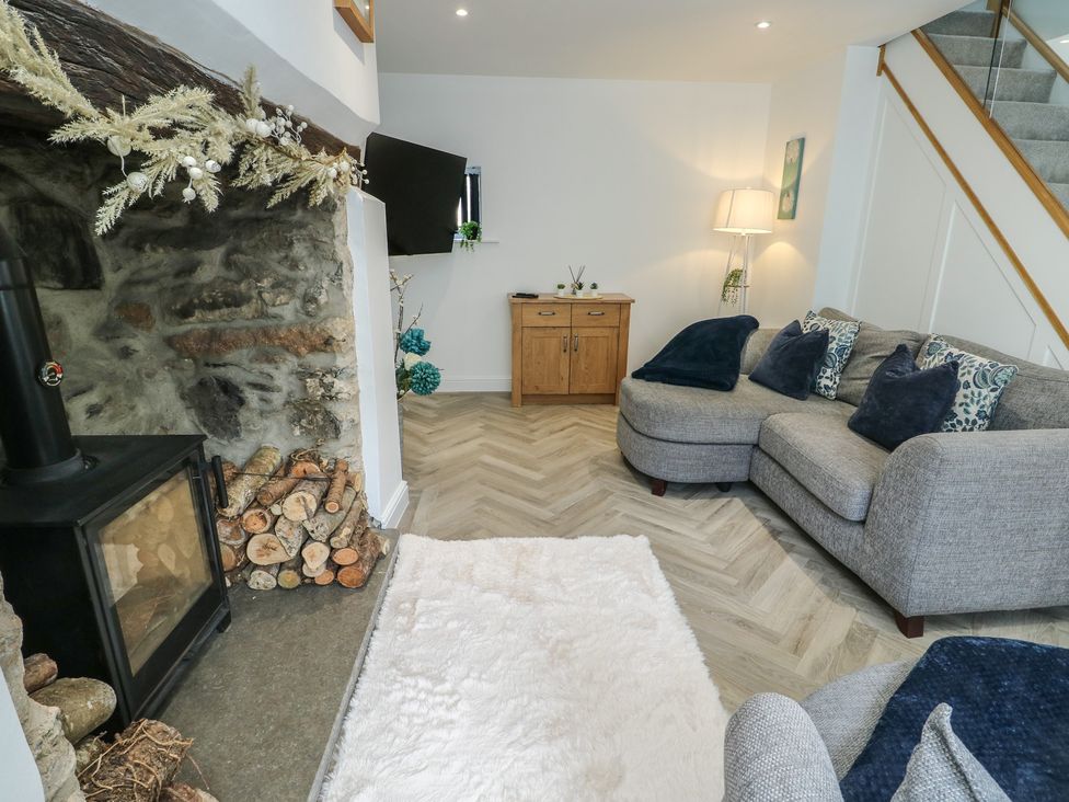 A living room with a fireplace and sofa at Rhows in Niwbwrch (Newborough)