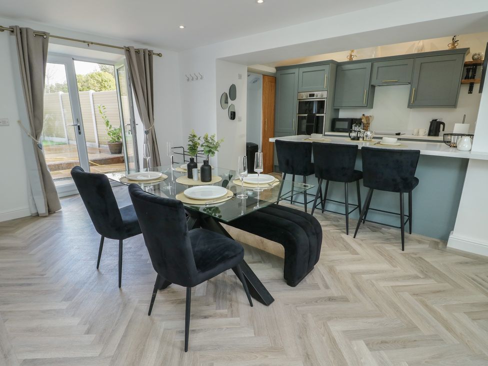A kitchen with a dining area including a glass table and chairs at Rhows in Niwbwrch (Newborough)
