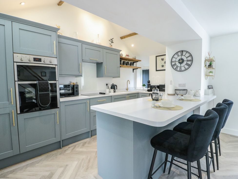 A kitchen with cabinets and bar stools at Rhows in Niwbwrch (Newborough)