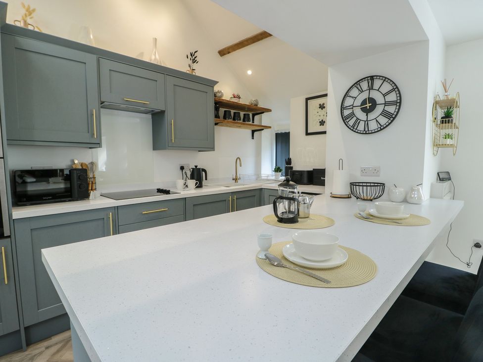 A kitchen with cabinets, countertop, sink, and dishes at Rhows, Niwbwrch (Newborough)