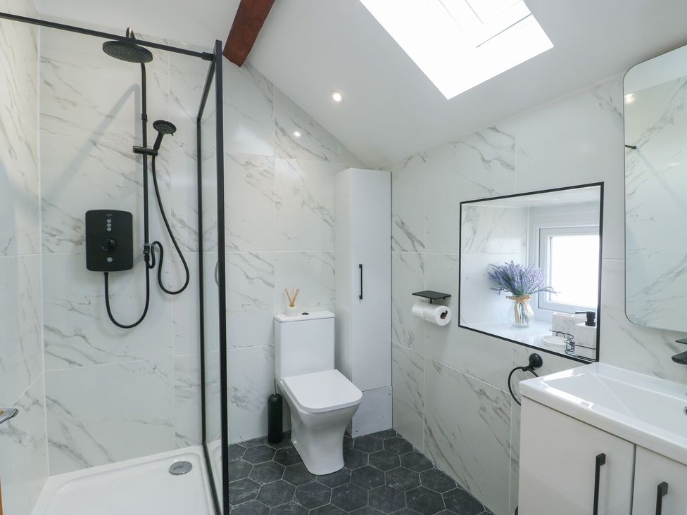 A bathroom with shower, toilet, and sink at Rhows in Niwbwrch (Newborough)