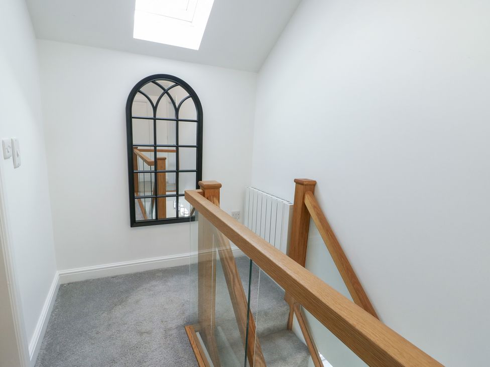 A hallway with a mirror and staircase at Rhows in Niwbwrch (Newborough)