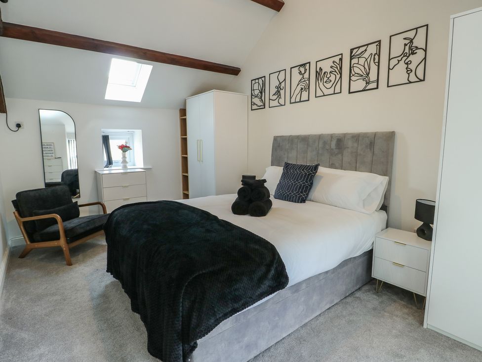 A bedroom with a bed and armchair at Rhows in Niwbwrch (Newborough)