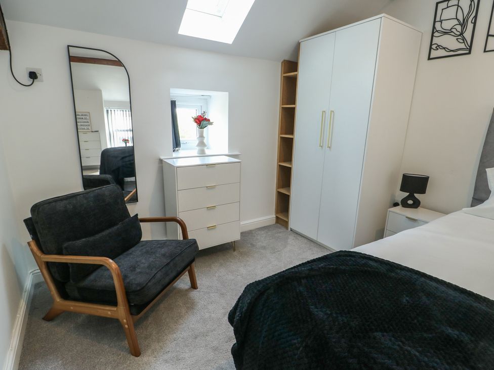 A bedroom with a bed, dresser, and a mirror at Rhows in Niwbwrch (Newborough)