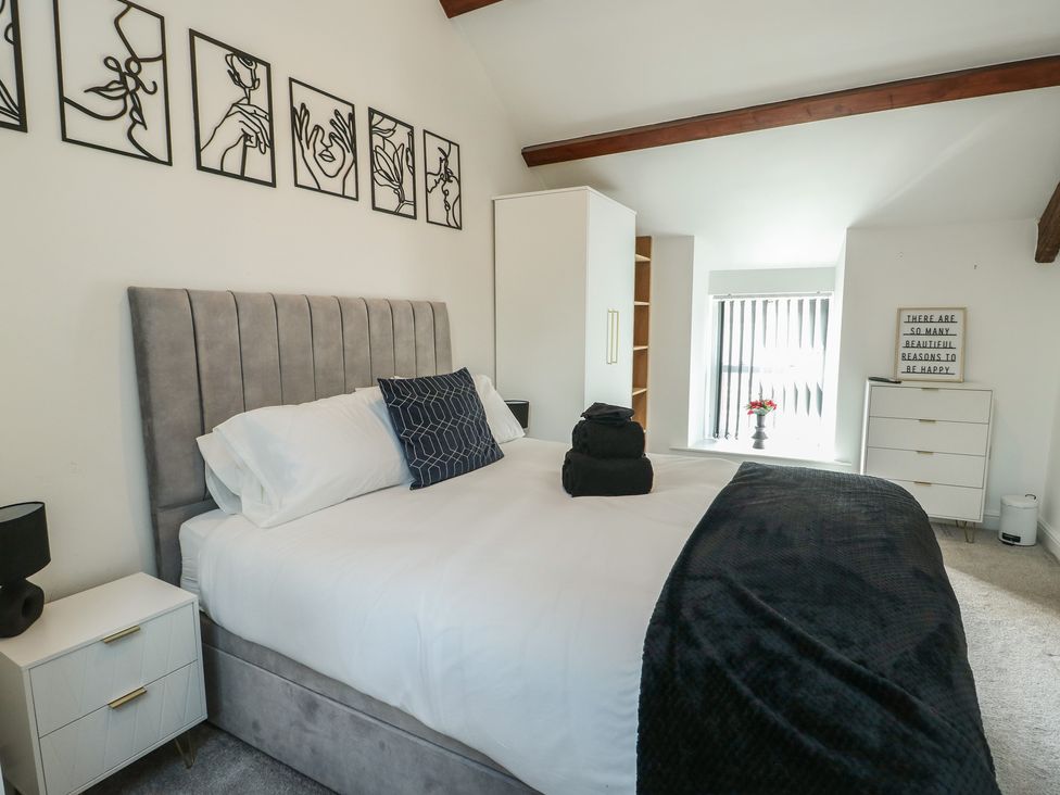 A bedroom with a bed and nightstand at Rhows in Niwbwrch (Newborough)