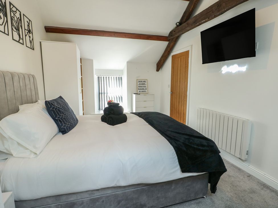 A bedroom with a bed and television at Rhows in Niwbwrch (Newborough)