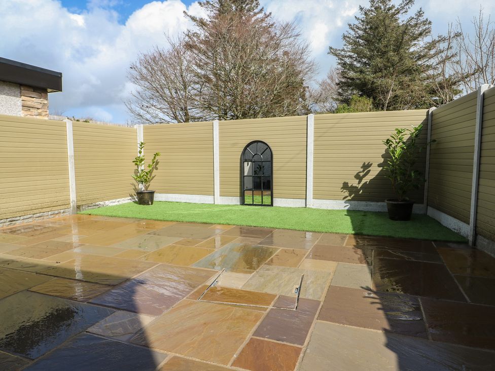 A garden with a stone patio and plants at Rhows in Niwbwrch (Newborough)