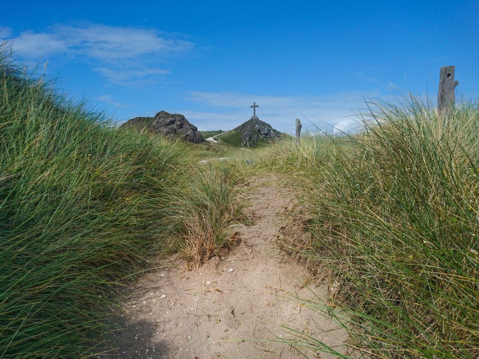 A path through grass leading to a cross on a hill at Hen Siop in Niwbwrch (newborough)