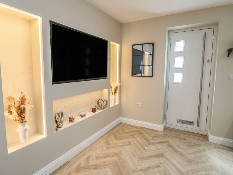 An entrance hall with a television and decorative shelves at Hen Siop in Niwbwrch (Newborough)