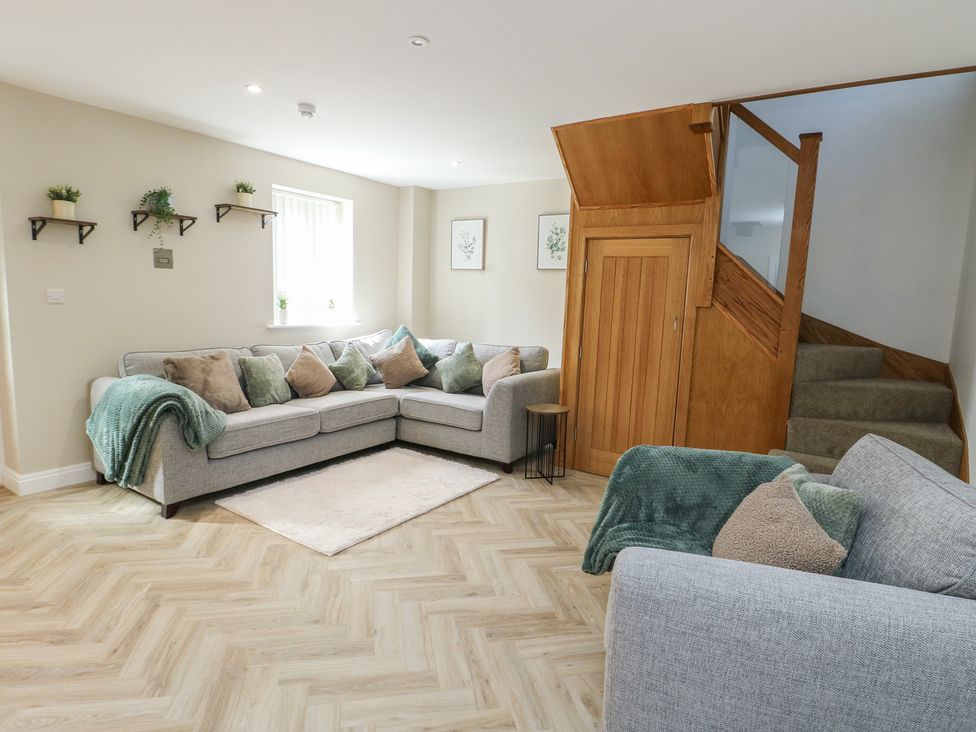 A living room with a sofa and stairs at Hen Siop Niwbwrch (Newborough)