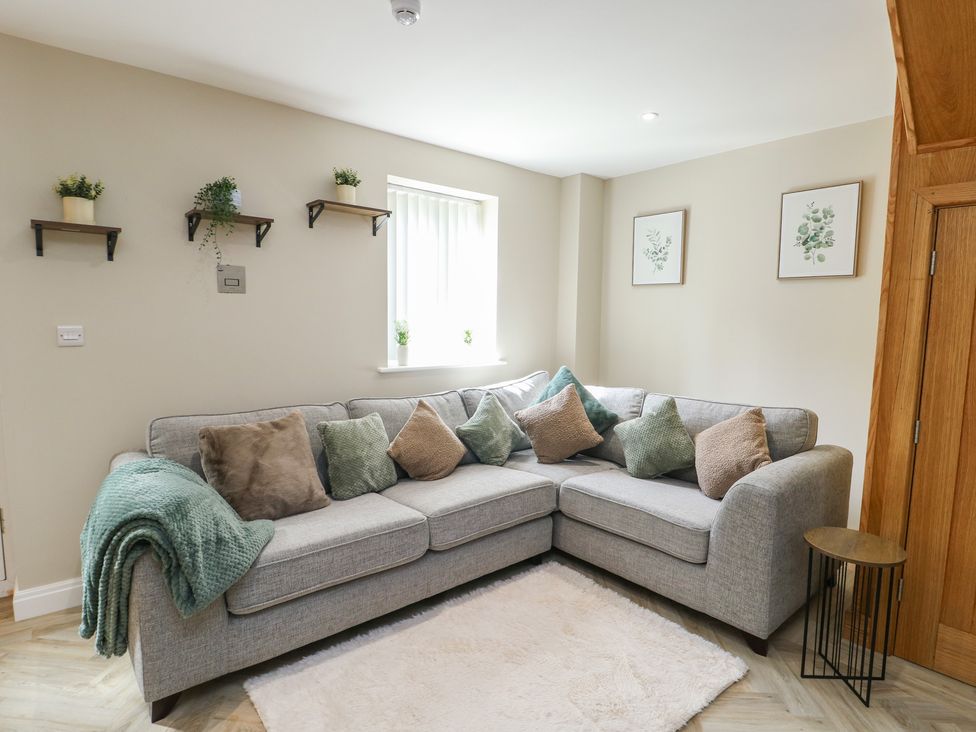 A living room with a sofa and shelves at Hen Siop in Niwbwrch (Newborough)