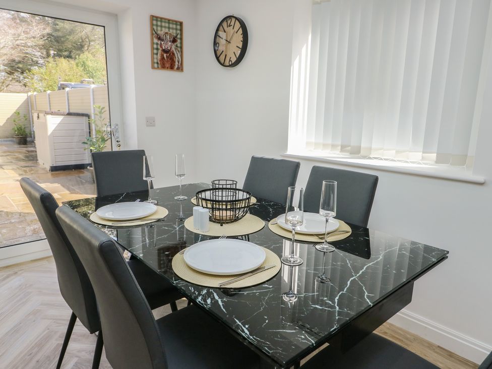 A dining room with a table set for six at Hen Siop in Niwbwrch (Newborough)