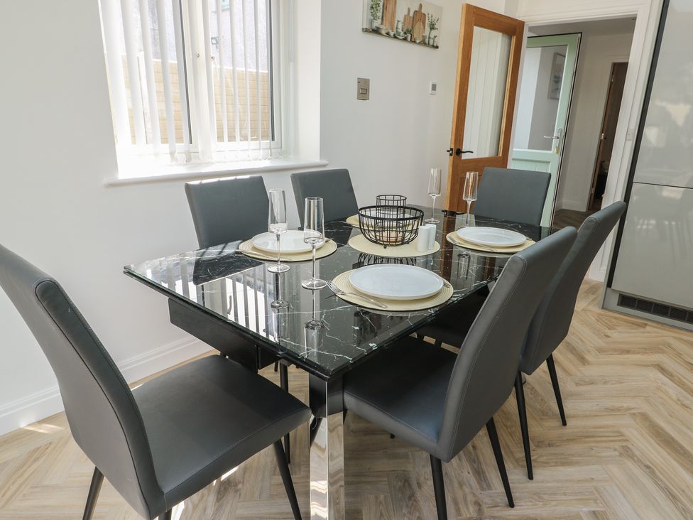 A dining room with a glass table and chairs at Hen Siop in Niwbwrch (Newborough)