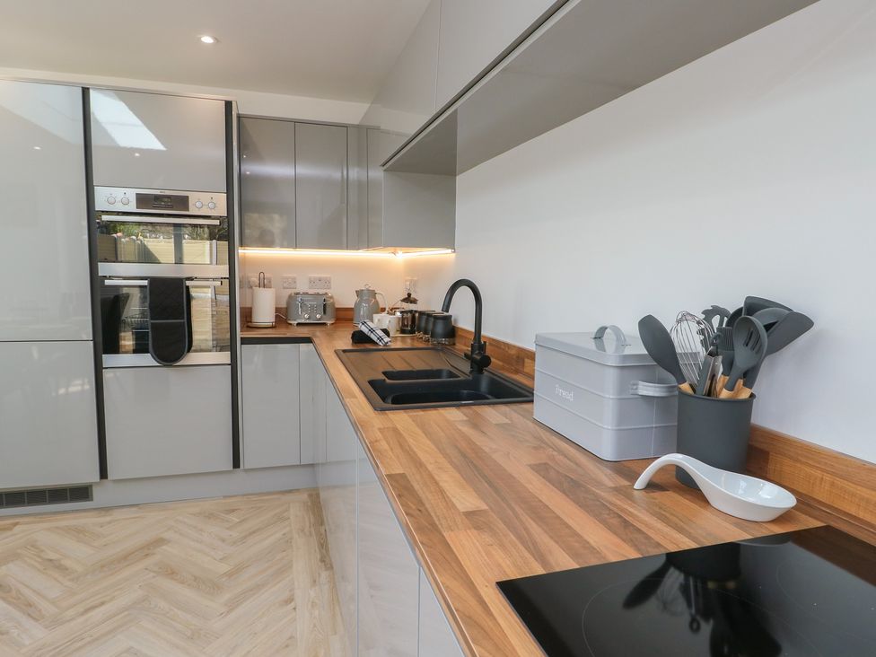 A kitchen with modern appliances and wooden countertop at Hen Siop Niwbwrch (Newborough)