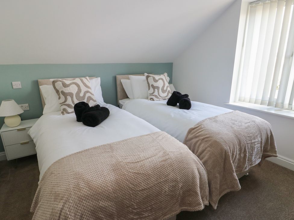 A bedroom with two single beds and a bedside table at Hen Siop Niwbwrch (Newborough)