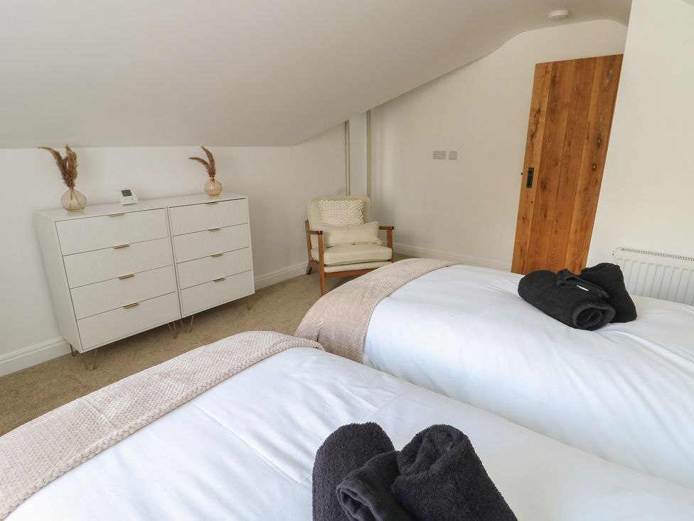 A bedroom with two beds and a dresser at Hen Siop in Niwbwrch (Newborough)