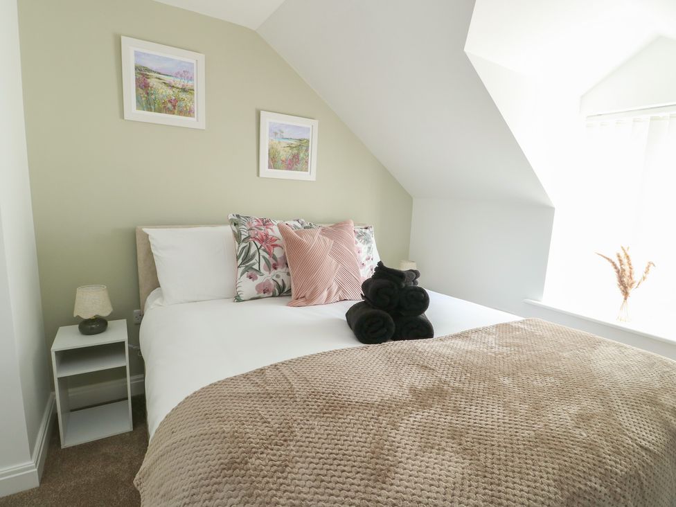 A bedroom with a bed and bedside table at Hen Siop in Niwbwrch (Newborough)