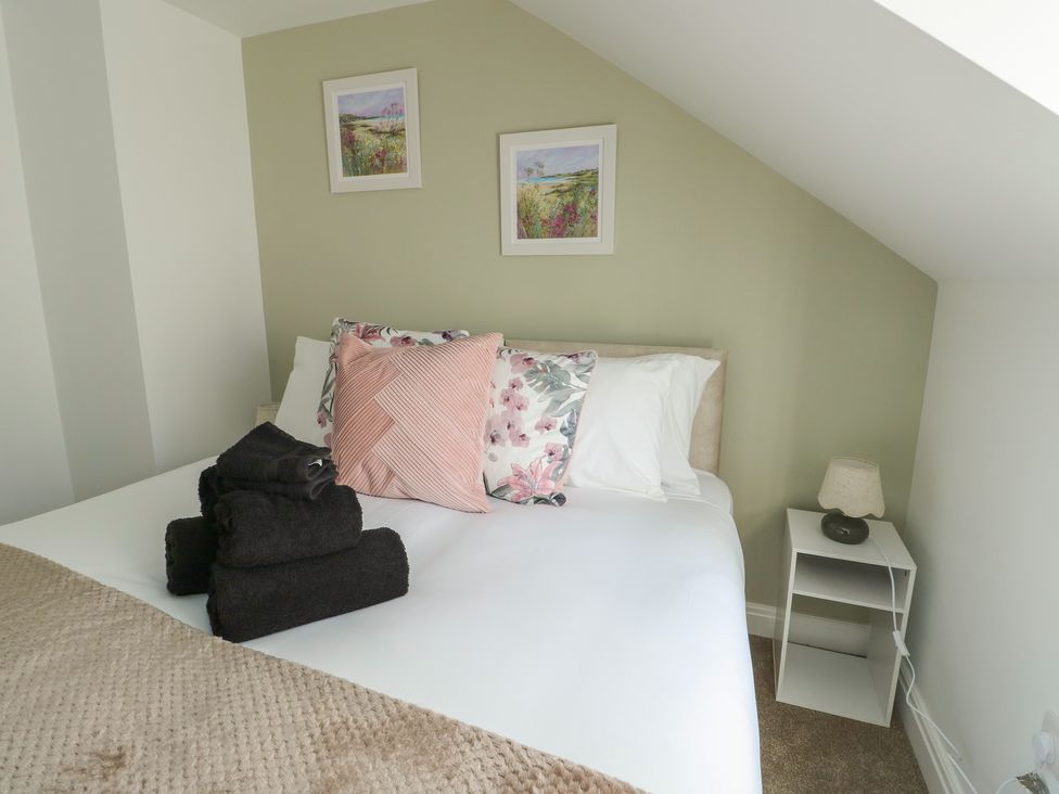 A bedroom with a bed and decorative items at Hen Siop, Niwbwrch (Newborough)