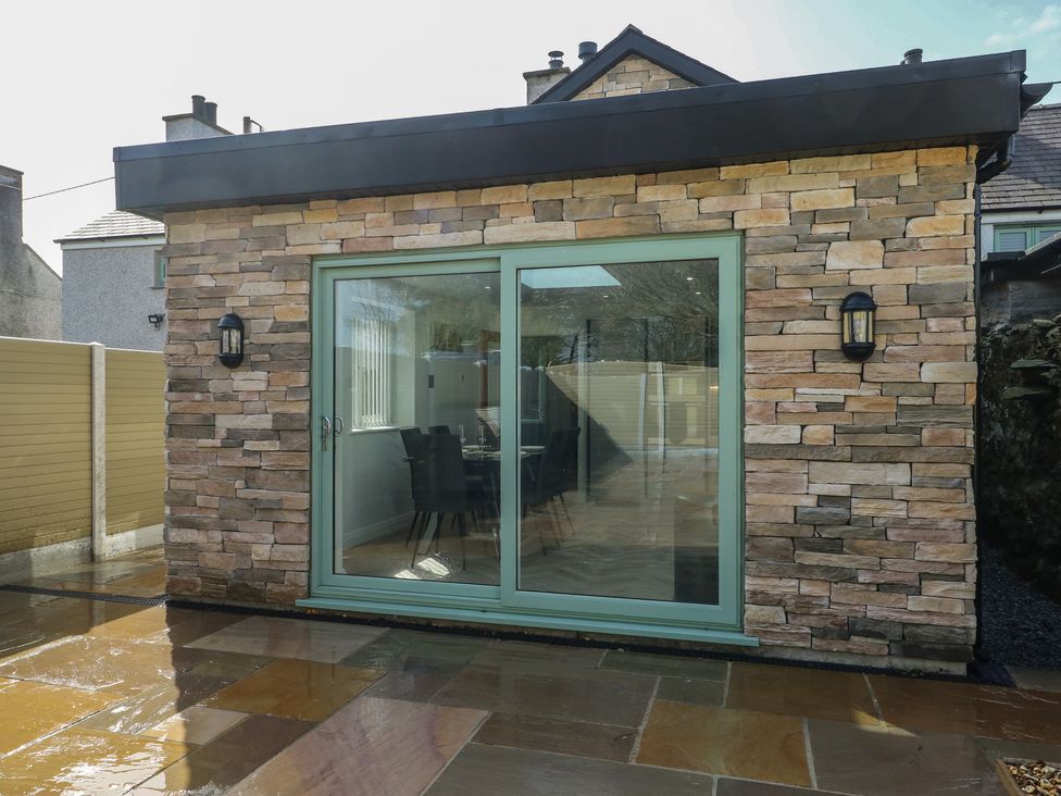 A building with a glass door and stone walls at Hen Siop in Niwbwrch (Newborough)
