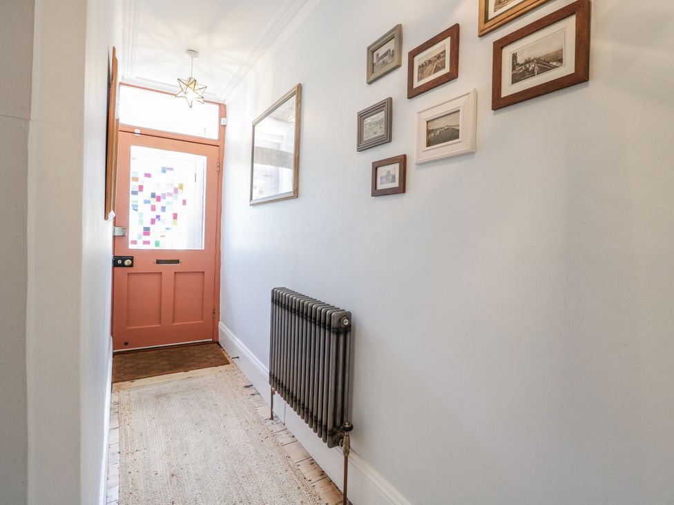 A hallway with a door and photographs on the wall at 18 Pakefield Road Lowestoft