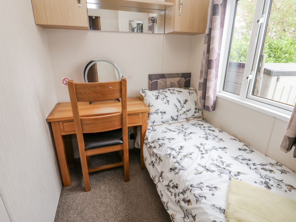 A bedroom with a bed and desk at Cate’s Cozy Cabin High Hesket near Lazonby