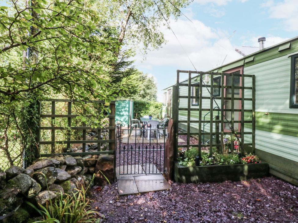 A garden with a gate leading to a seating area at Meadow Island Caravan
