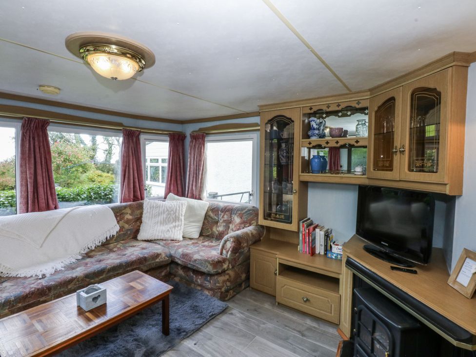 A living room with a sofa and television at Meadow Island Caravan