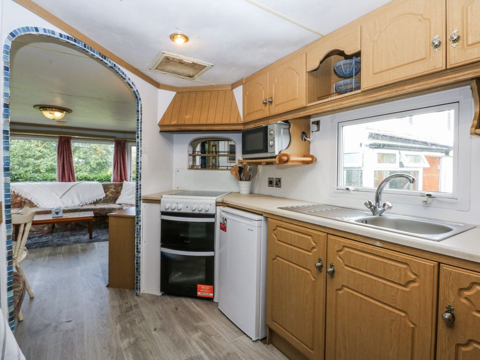 A kitchen with appliances and a table at Meadow Island Caravan