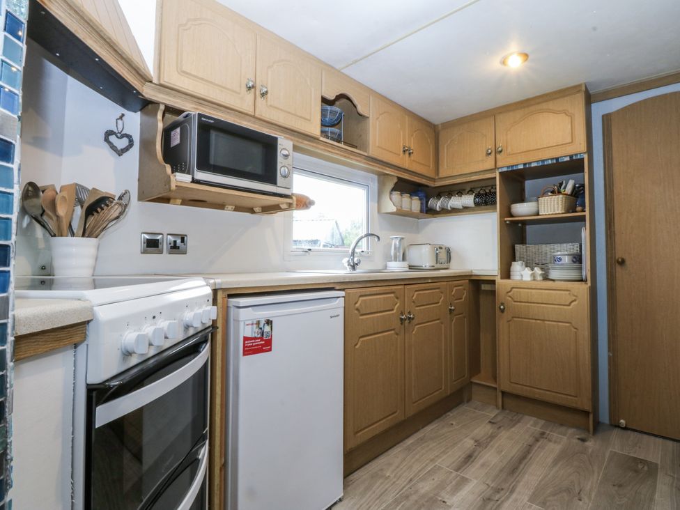 A kitchen with cabinets and appliances at Meadow Island Caravan