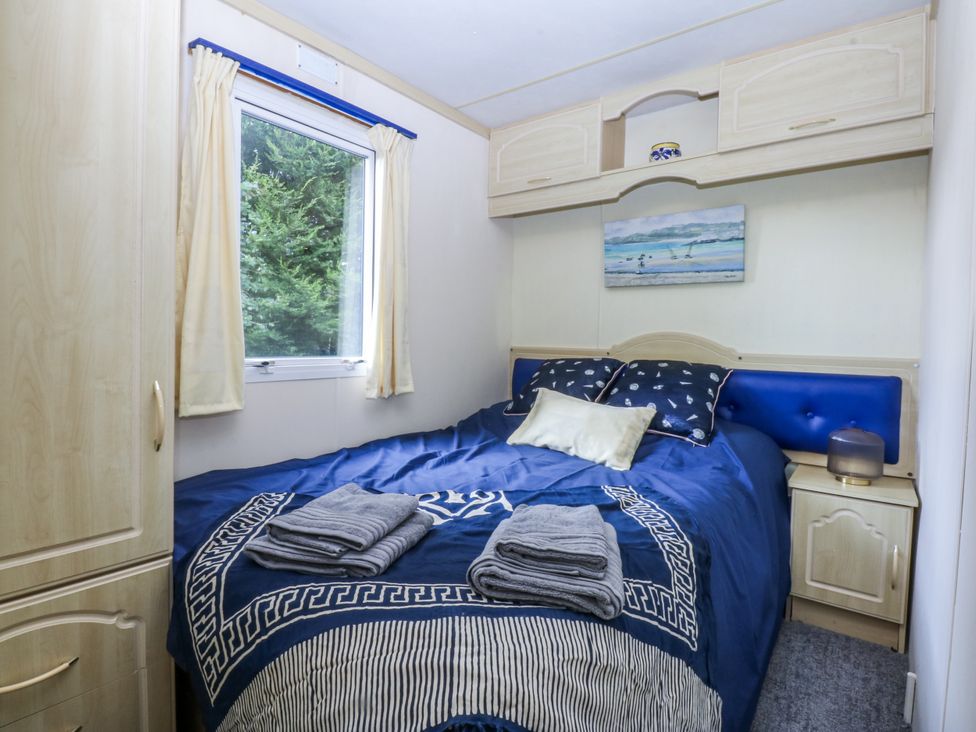 A bedroom with a bed and wardrobe at Meadow Island Caravan