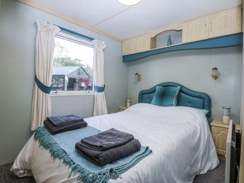 A bedroom with a bed and window at Meadow Island Caravan