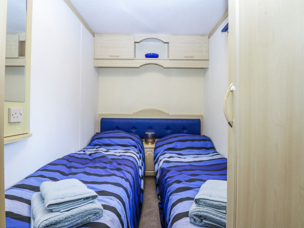 A bedroom with two beds and a mirror at Meadow Island Caravan
