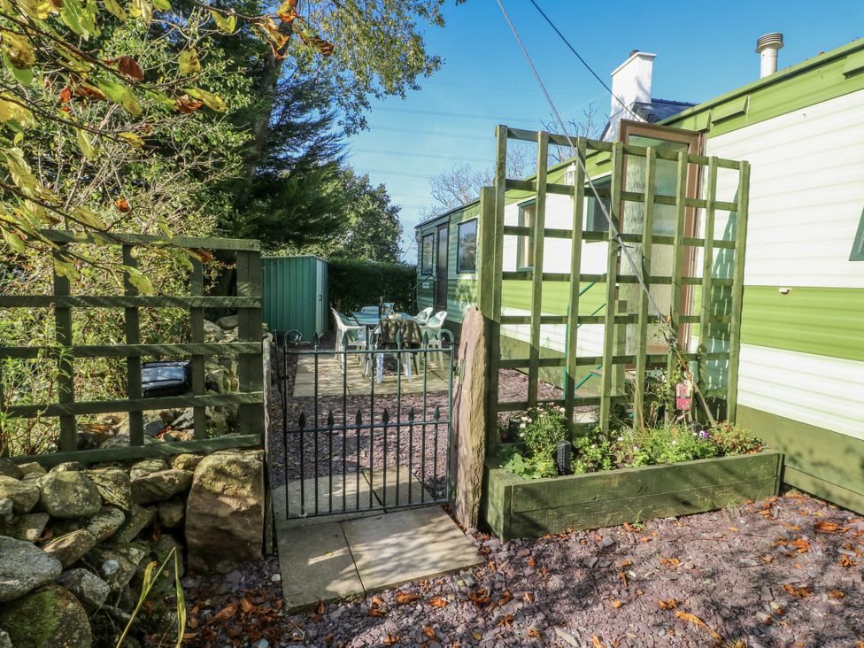 An outdoor area with a gate and table with chairs at Meadow Island Caravan in Penygroes