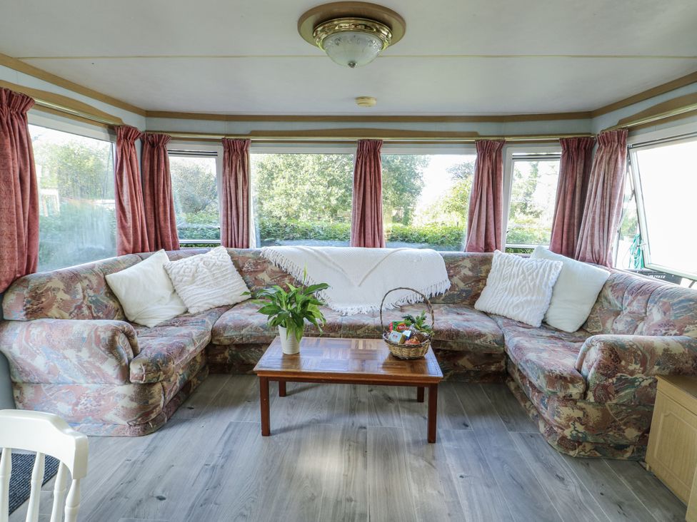 A living room with a sofa and table at Meadow Island Caravan in Penygroes