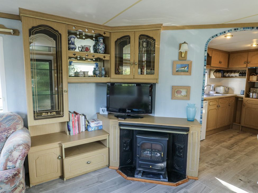 A living room with a television and fireplace at Meadow Island Caravan in Penygroes