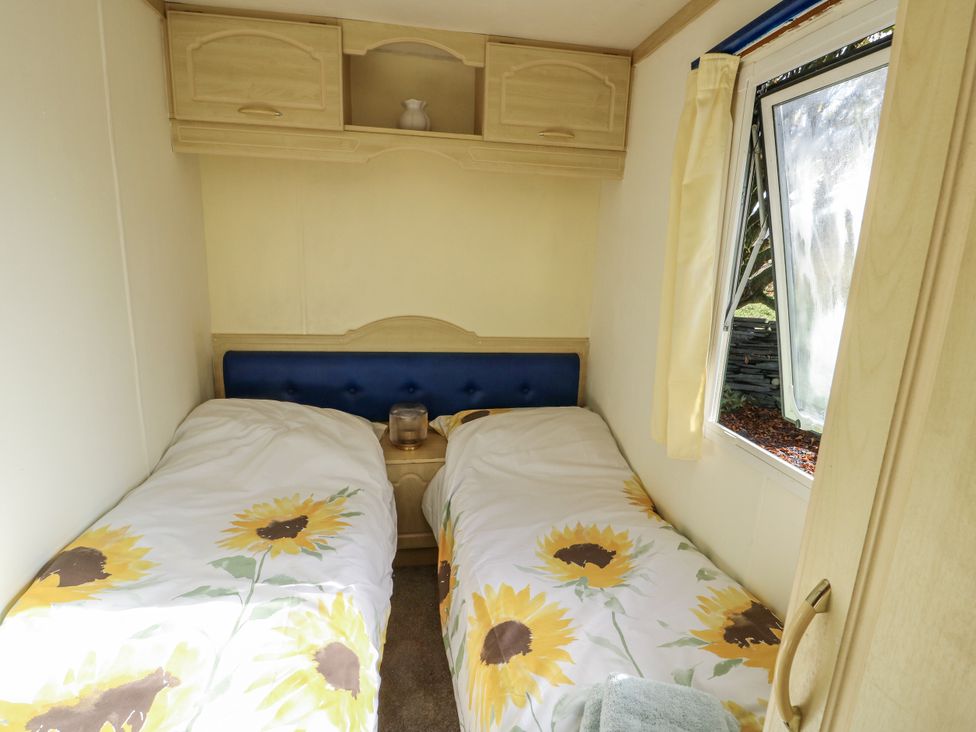 A bedroom with two beds and a window at Meadow Island Caravan Penygroes