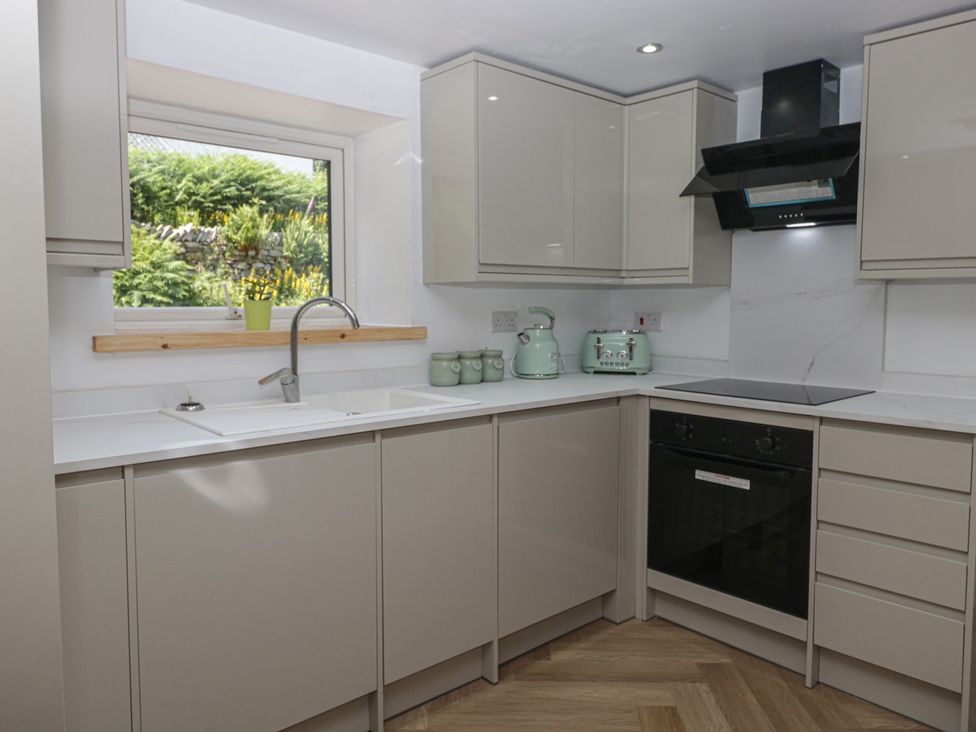 A kitchen with cabinets, a sink, a stove and a window at Old Post Office Cottage in Ulverston