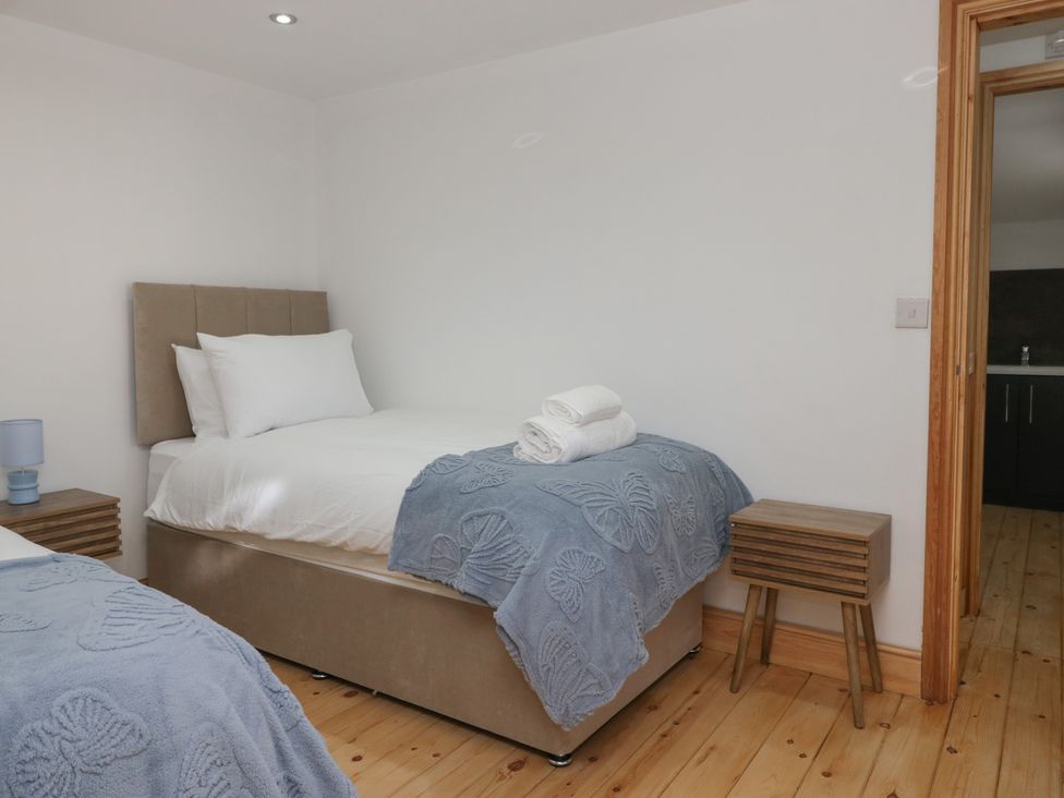 A bedroom with two beds and a nightstand at Old Post Office Cottage in Ulverston