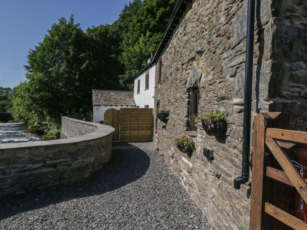 An outdoor path leading to a stone house at Old Post Office Cottage Backbarrow near Newby Bridge