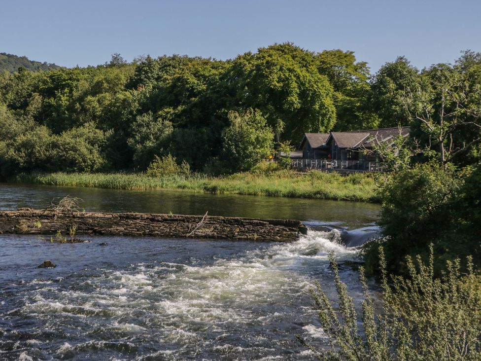 A river with a building by the water and trees near the shoreline at Old Post Office Cottage Backbarrow near Newby Bridge