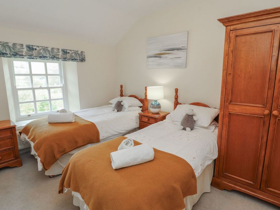 A bedroom with two beds and a wardrobe at Deer How Farm in Patterdale near Glenridding