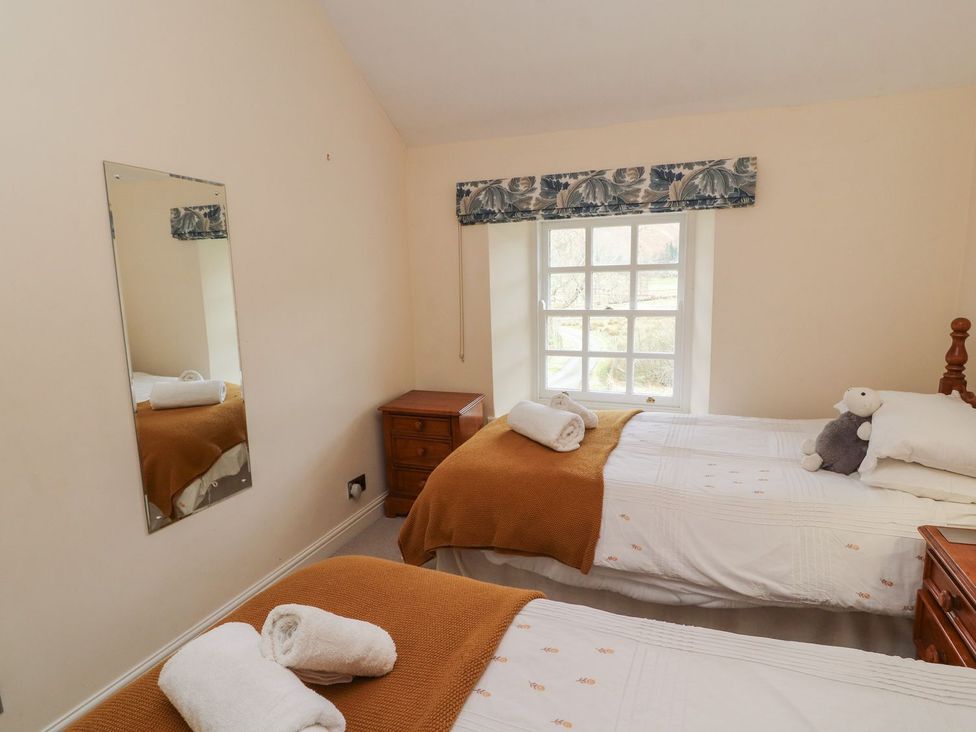 A bedroom with two beds and a mirror at Deer How Farm in Patterdale near Glenridding
