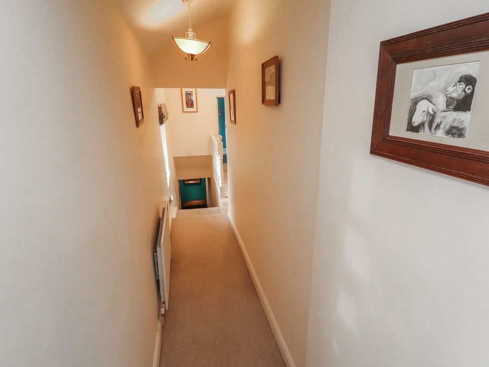 A hallway with framed artwork and a staircase at Deer How Farm in Patterdale near Glenridding