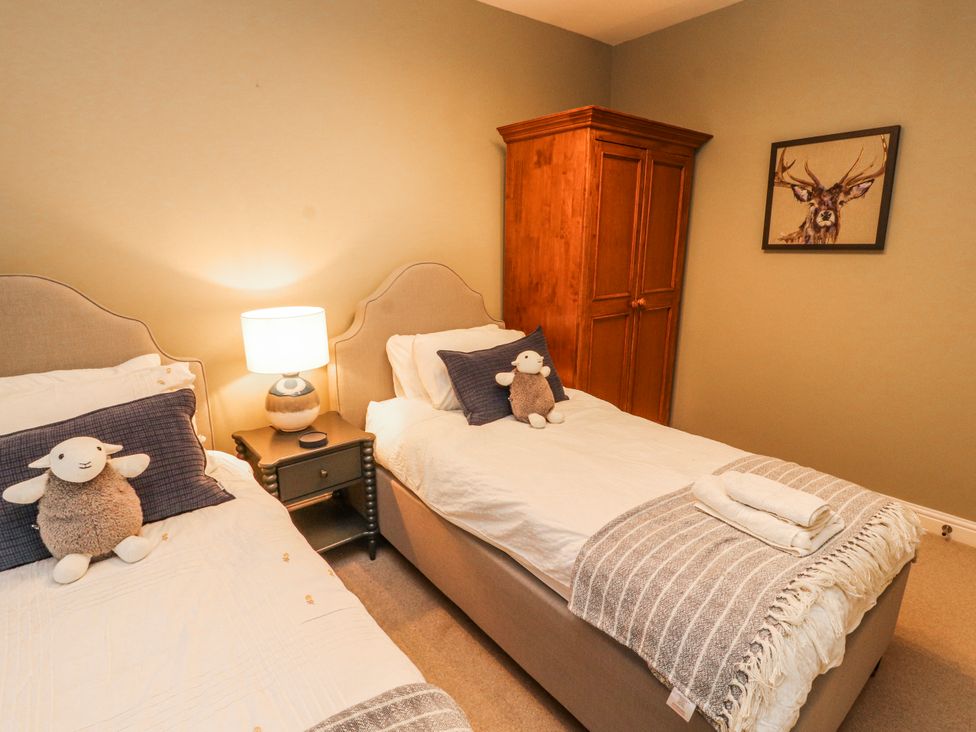 A bedroom with two single beds and a wardrobe at Deer How Farm in Patterdale near Glenridding