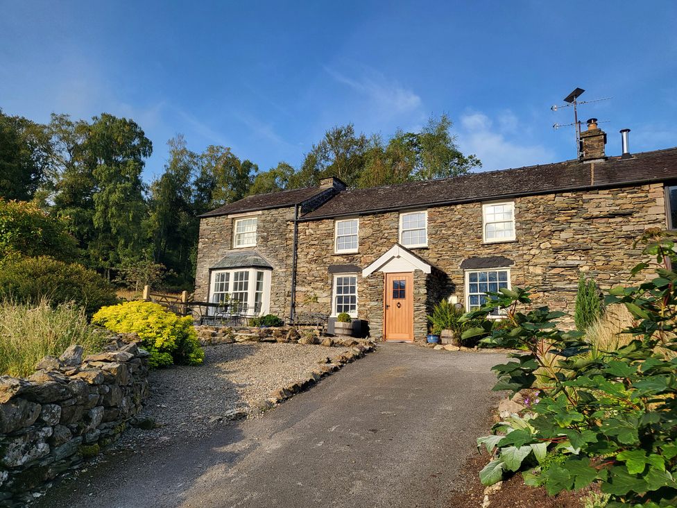 A stone house with a garden and driveway at Deer How Farm in Patterdale near Glenridding