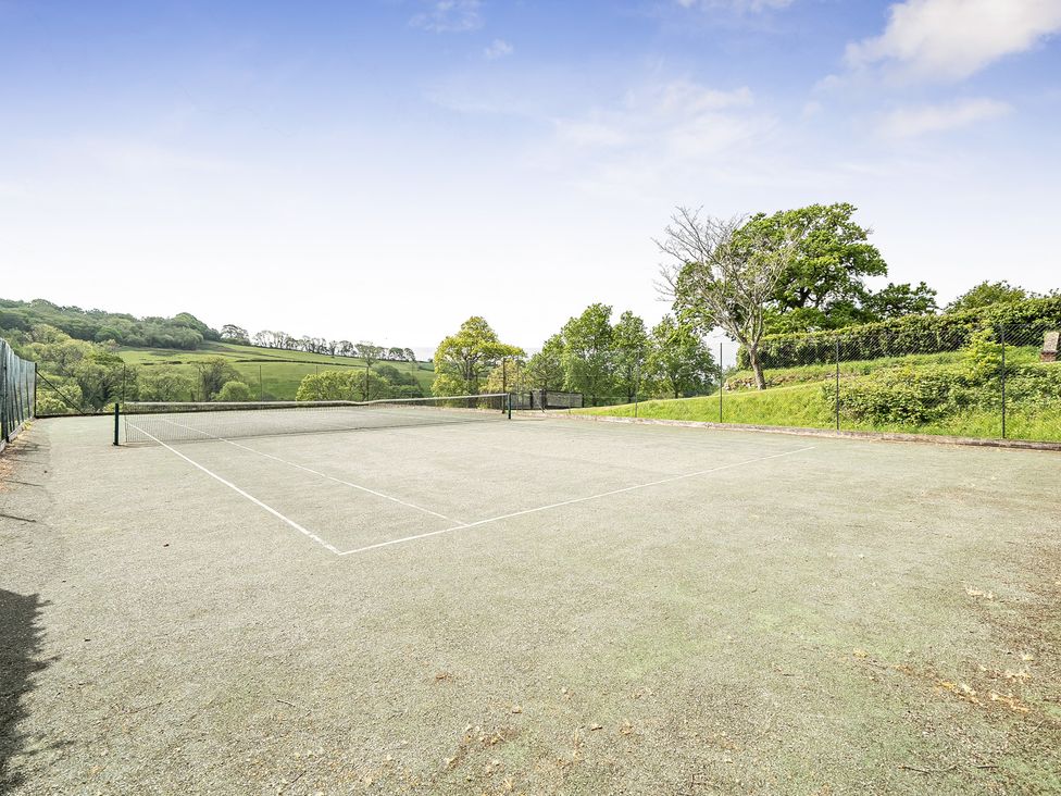 A tennis court surrounded by trees at Harcombe House Accessible Pet Free Bungalow Sleeps 6 Chudleigh